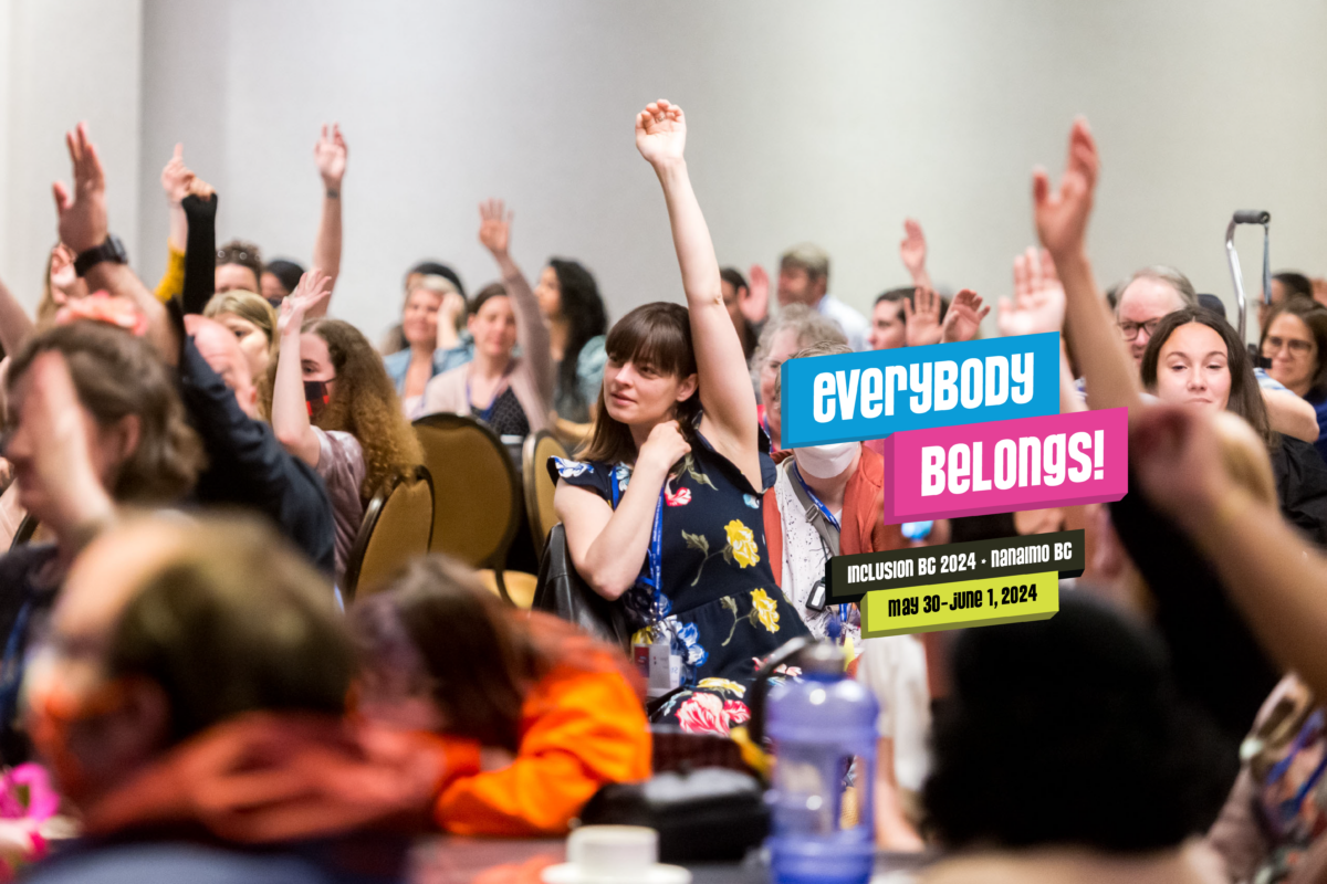 A ballroom full of people seated at round tables wearing conference lanyards looking to the left and raising one of their hands high in the air. Text to the right reads: Everybody Belongs, Inclusion BC 2024, Nanaimo BC, May 30 - June 1, 2024