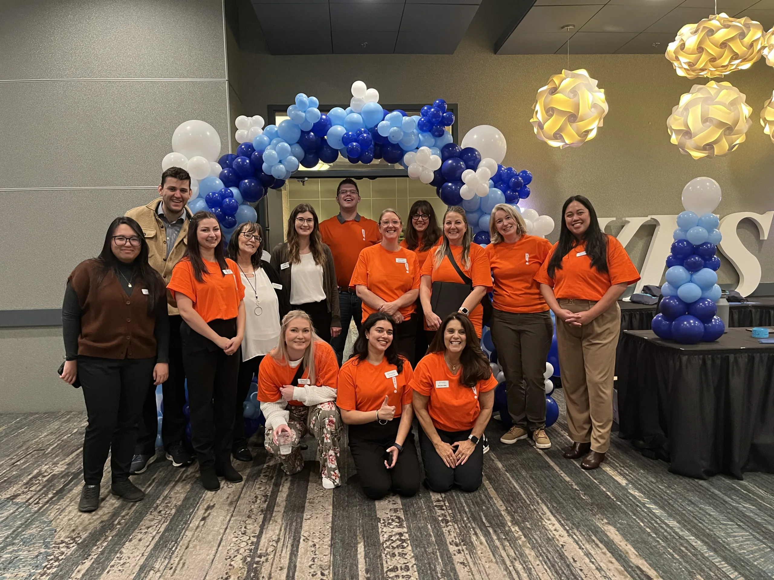 Group of volunteers standing under a balloon arch.